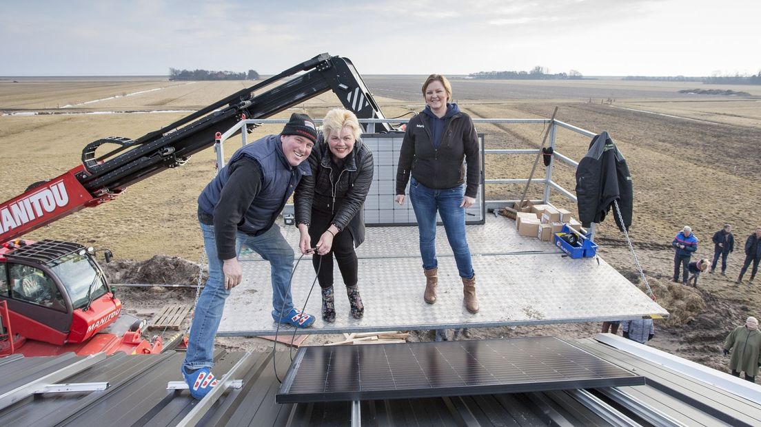 Burgemeester Ineke van Gent (midden) plaatst het eerste van 750 zonnepanelen
