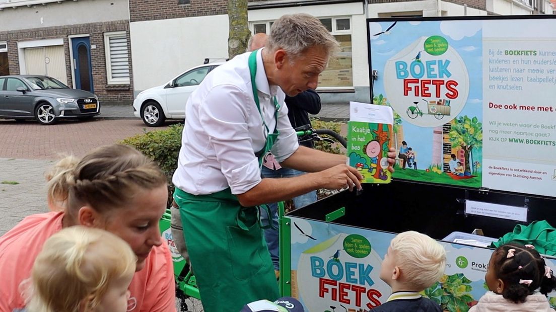 Wethouder van Willigen laat het boekje zien waar hij de kinderen straks uit gaat voorlezen.