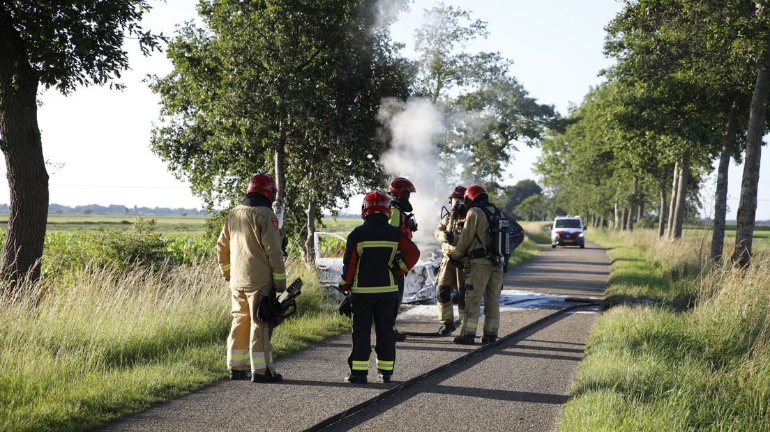 Brandweermannen bij de uitgebrande auto in Midwolde