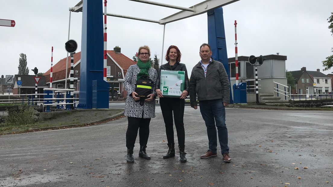 Monique Bruggenkamp, Annemarie Timmermans en Arwoud Snippe met de AED die binnenkort bij de brug wordt opgehangen (Rechten: RTV Drenthe / Jeroen Willems)