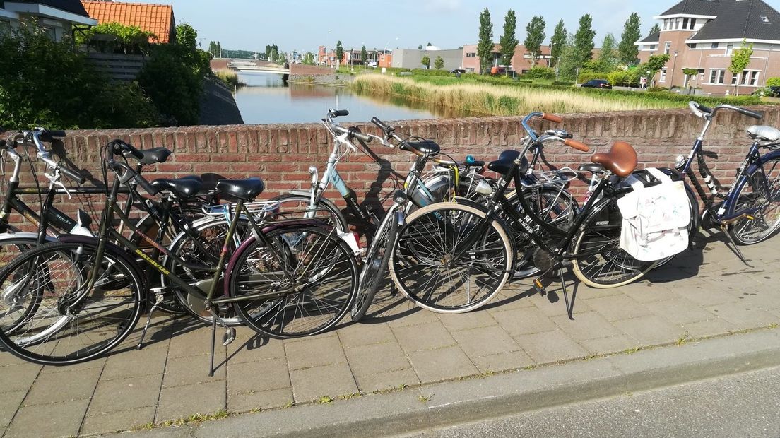 Jongeren hangen fietsen aan brug