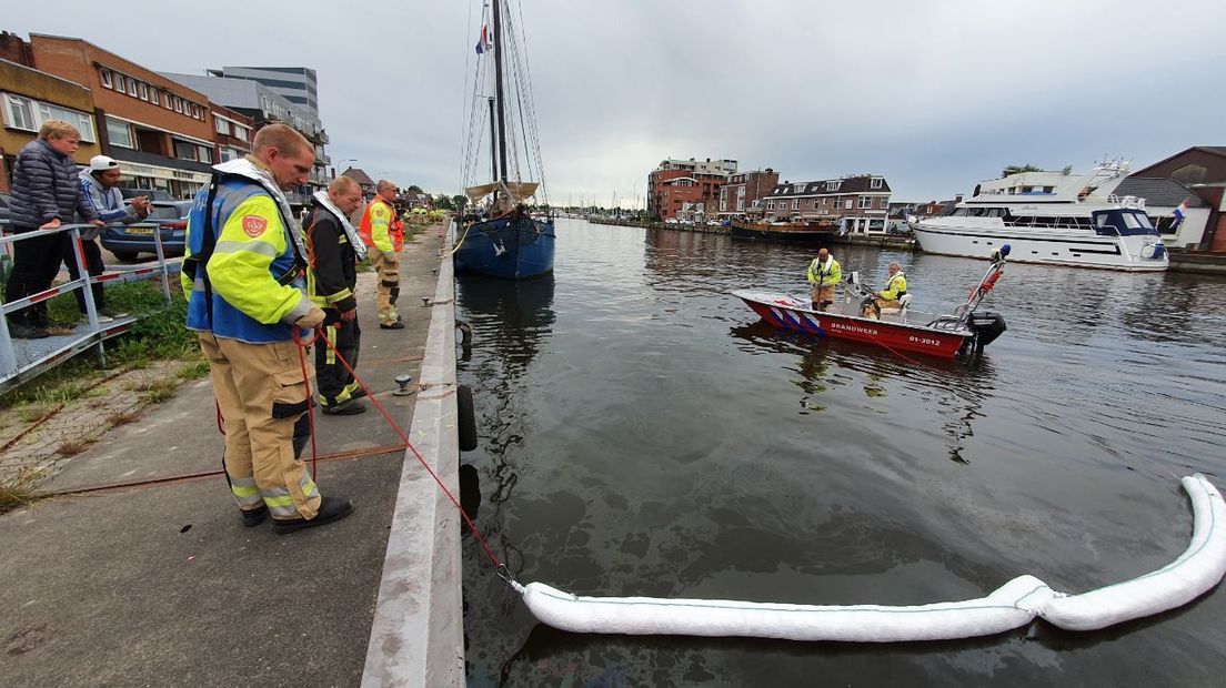 De brandweer plaatst oliebooms in het Oude Eemskanaal in Farmsum