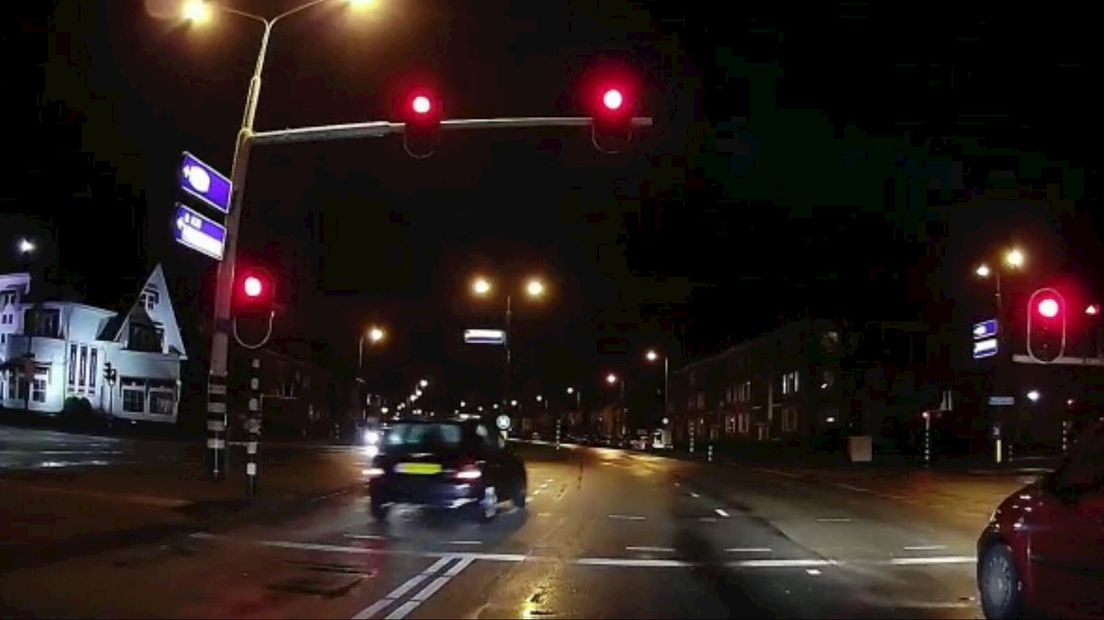 De bestuurder van een zwart autootje rijdt oerend hard door het rode licht