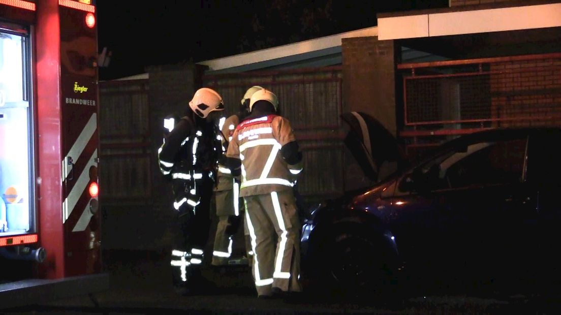 Brandweerlieden bij de brandende auto