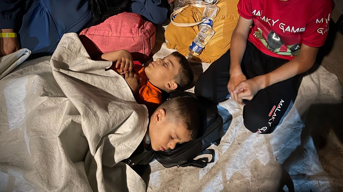 Twee jongens proberen de slaap te vatten in de buitenlucht voor het aanmeldcentrum