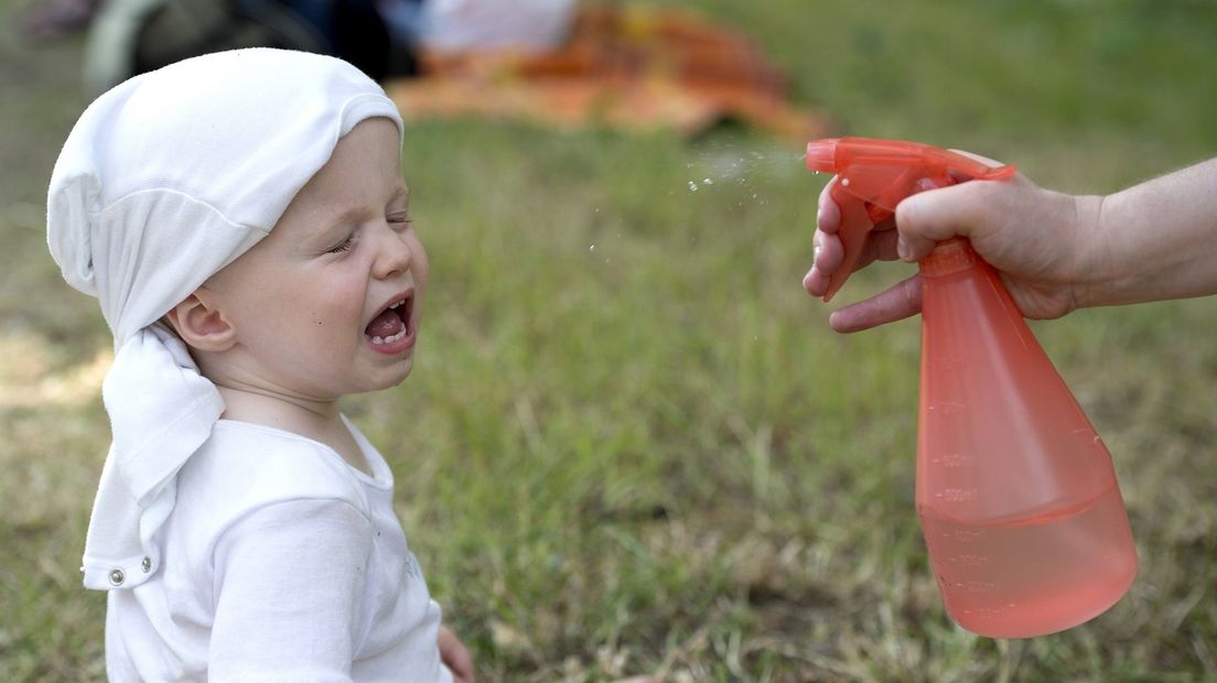 Een kind krijgt wat water in het gezicht voor de verkoeling