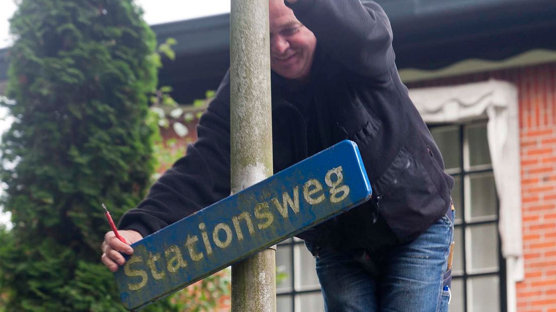 Iemand zit aan het straatnaambord van de Stationsweg