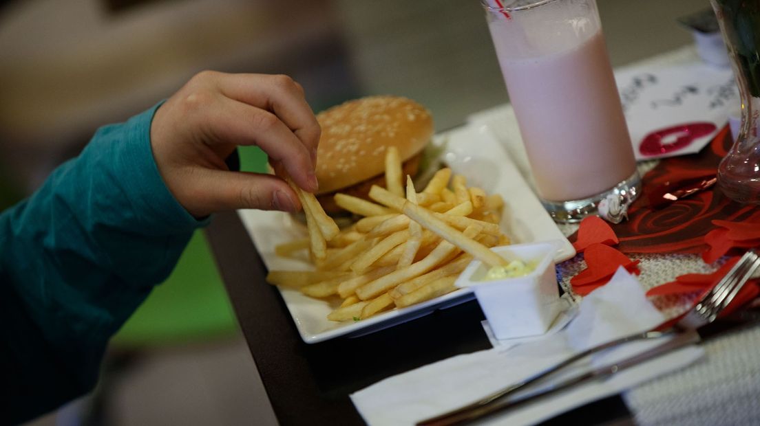 Een bezoeker van McDonald's neemt een patatje.