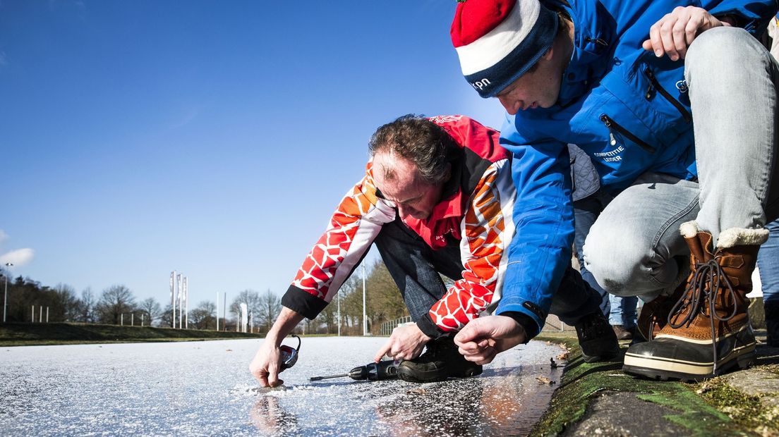Competitieleider marathon van de KNSB Willem Hut (R) meet met Jaap in 't Veld de ijsdikte