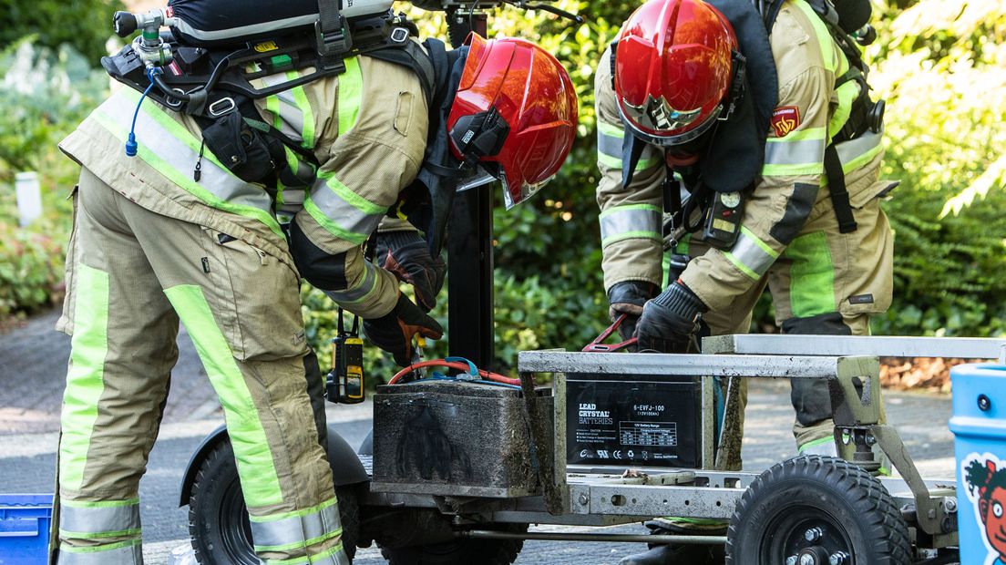 Brandweermannen verwijderen oververhitte accu van bolderkar.