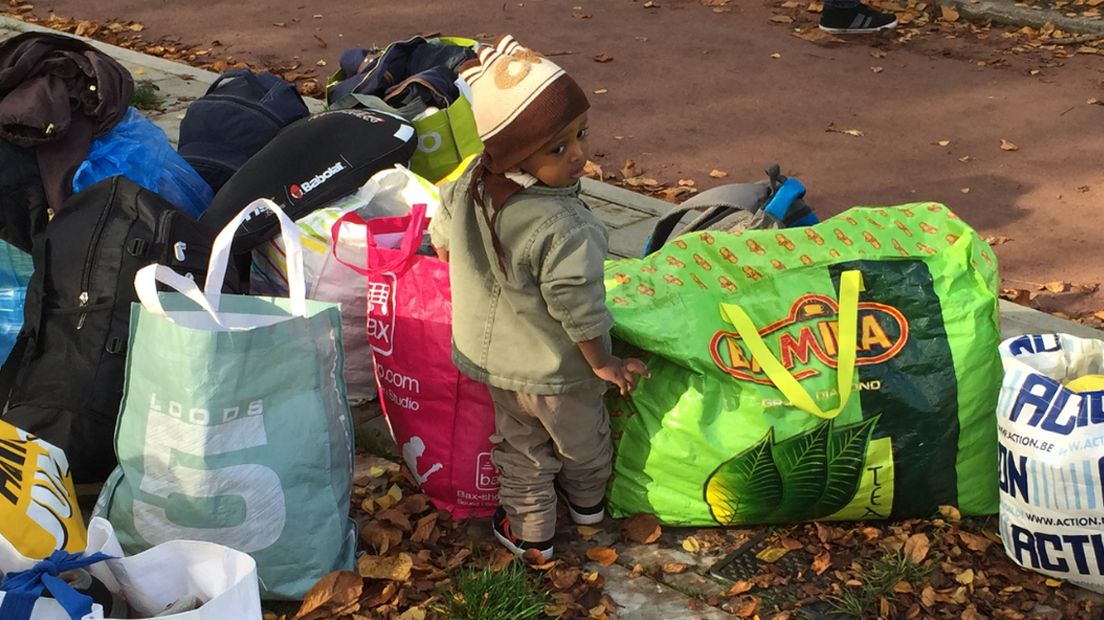 Een kindje tussen de tassen die boze asielzoekers in Den Haag op straat hebben neergezet
