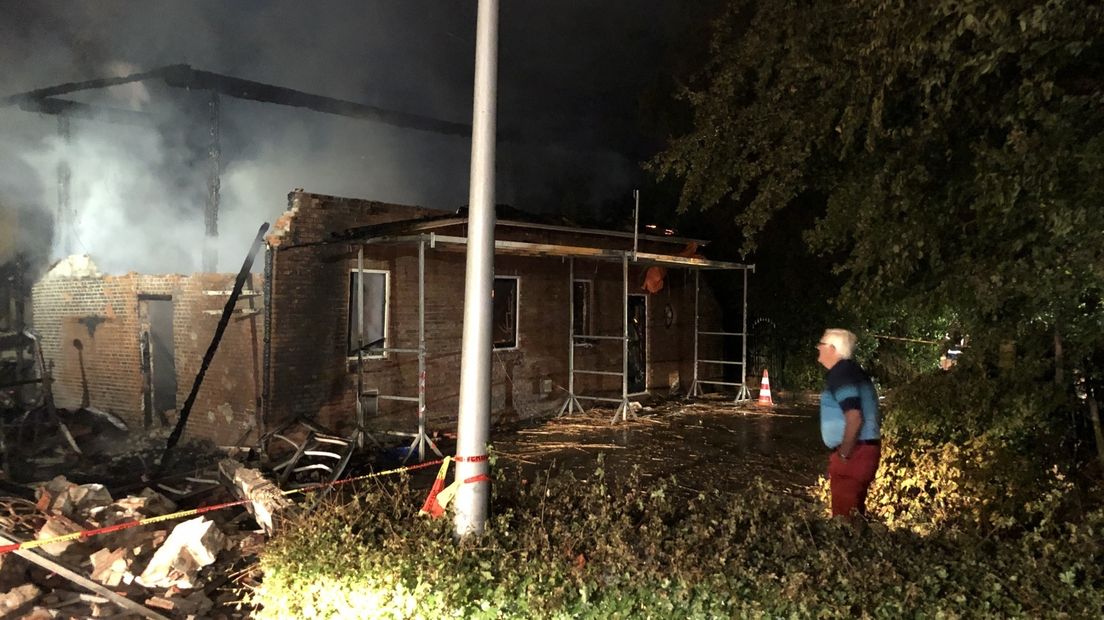 De buurman kijkt naar de afgebrande boerderij