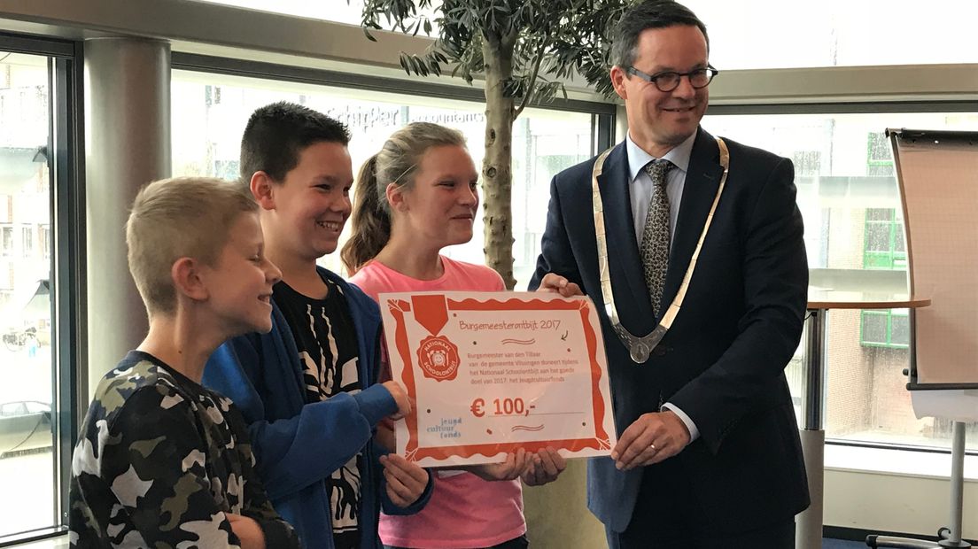 De kinderen kregen een cheque van honderd euro van de burgemeester om te doneren aan een het Jeugdcultuurfonds