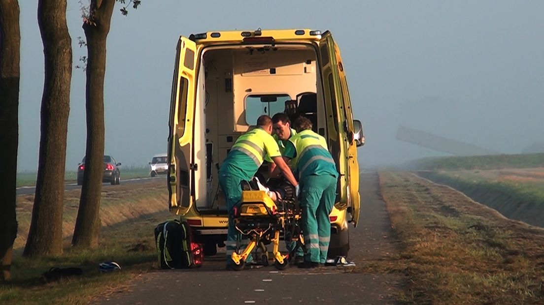 Ambulancepersoneel legt de gewonde wielrenner in de ambulance