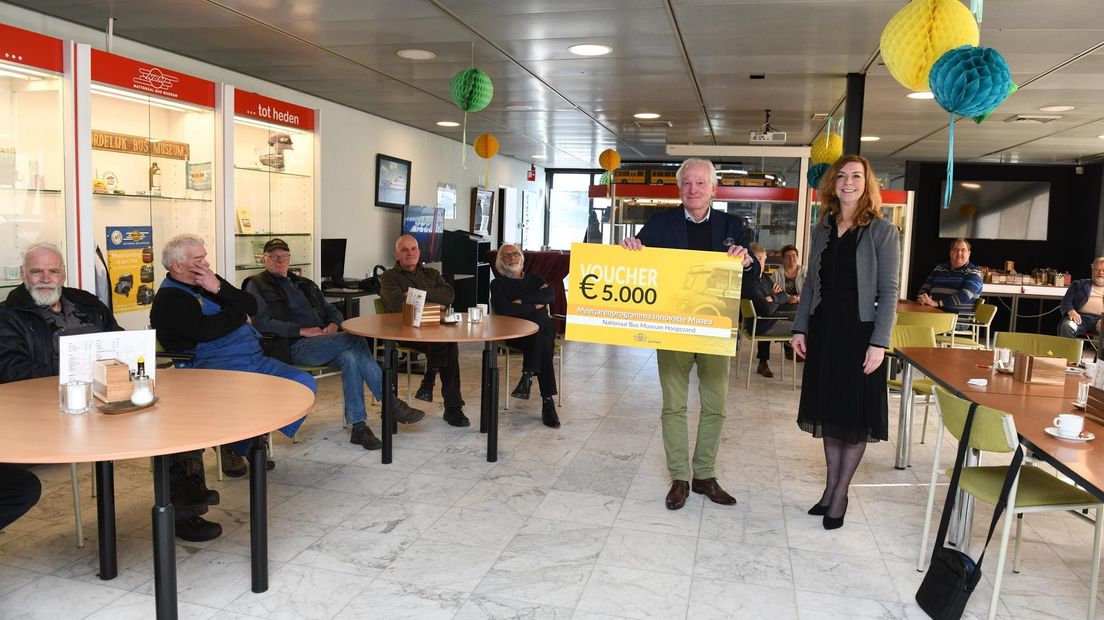 Gedeputeerde Mirjam Wulfse overhandigt de voucher aan museumdirecteur Rob Bezema.