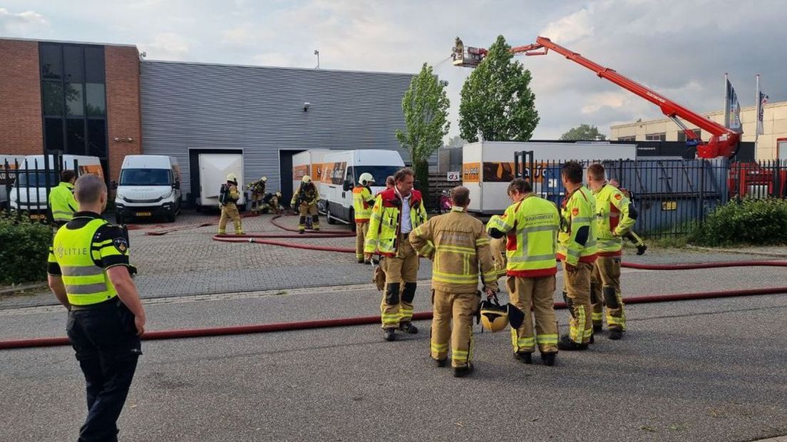 De brandweer is met man en macht bezig de brand in de werkplaats te bestrijden.