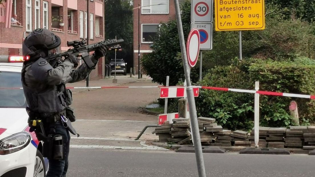 Zwaar bewapende agenten in Almelo waar een man met een kruisboog op het balkon staat.