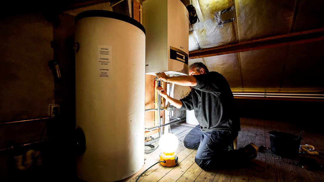 Een monteur sleutelt aan een warmtepomp