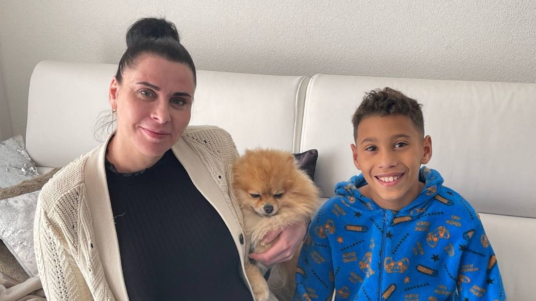 Kristina zit met haar zoon Riviënno en hond op de bank