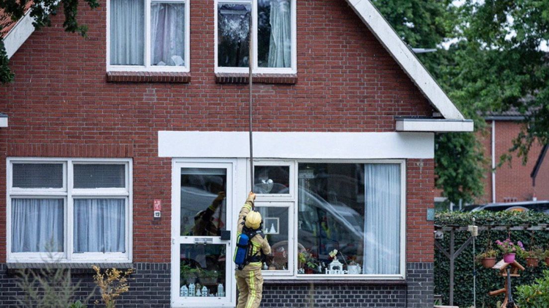 De brandweer slaat een raam van de woning in om te luchten (Rechten: De Vries Media)