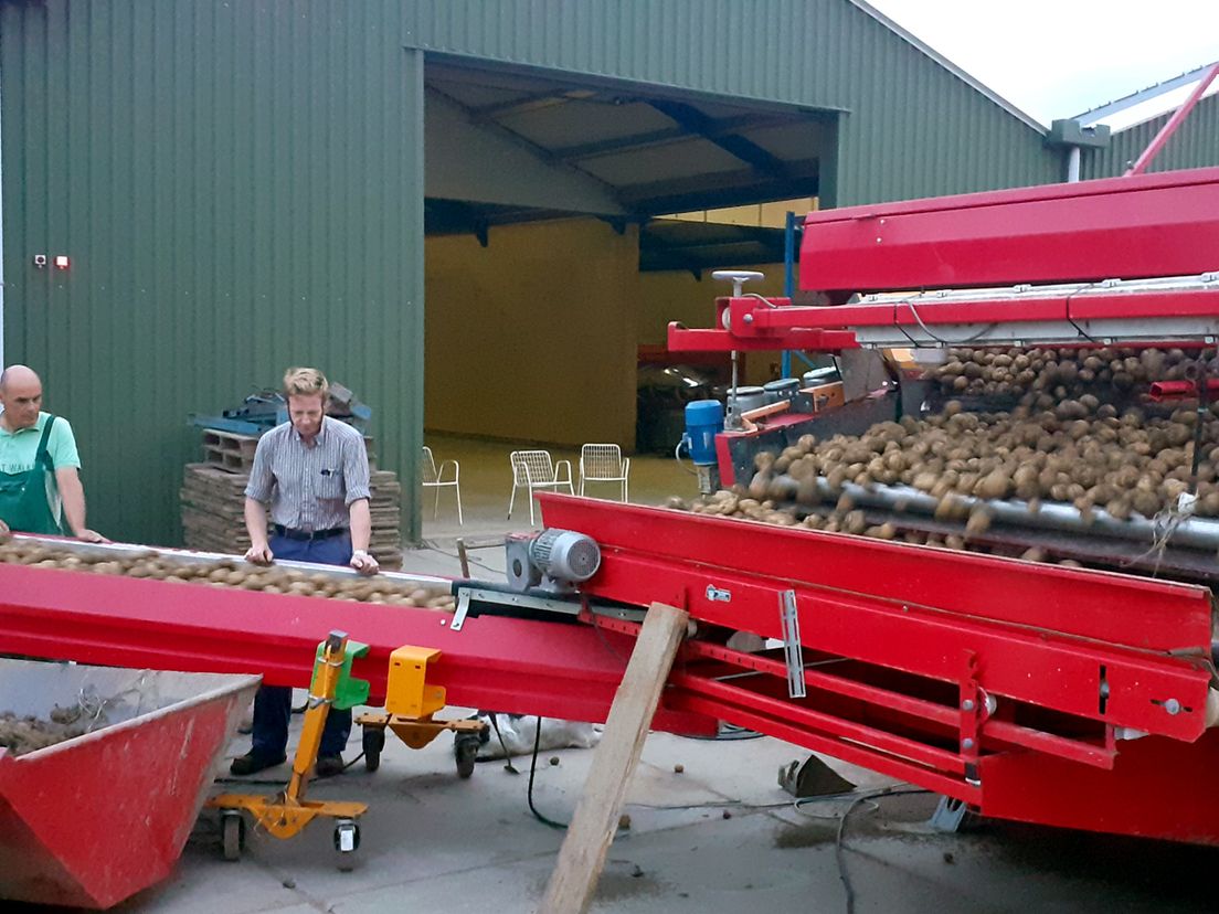 Boer Kees Trouw bij de aardappelsorteermachine met medewerker Jurphaas Lugtenburg