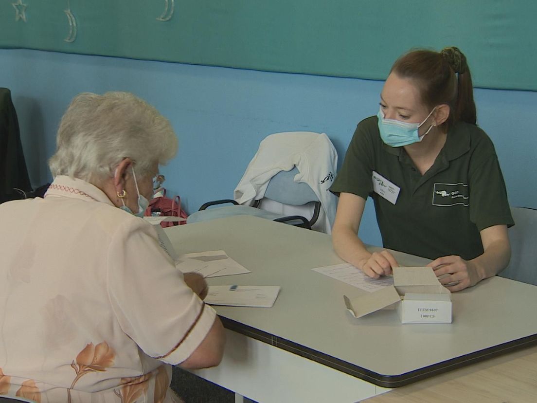 Medewerkers van de GGD wijzen bewoners in Rotterdam-Zuid op de mogelijkheid om zich zonder afspraak te laten vaccineren tegen corona.