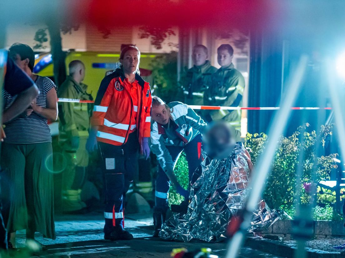 De gewonde man wordt geholpen op de stoep voor de woning in Dordrecht