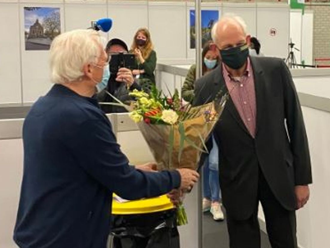 Burgemeester Cor Lamers geeft een bloemetje aan de inwoner die de eerste prik kreeg
