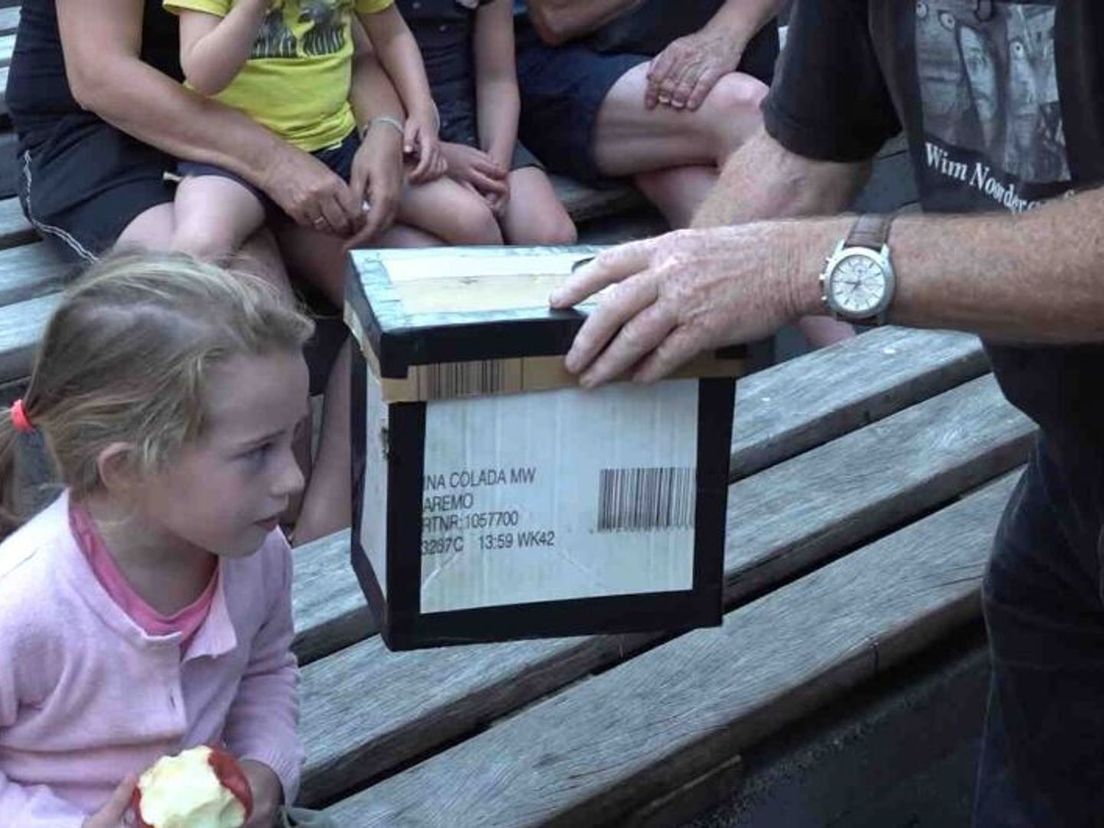 De kabouter in de doos wordt aandachtig bekeken door een van de aanwezige kinderen