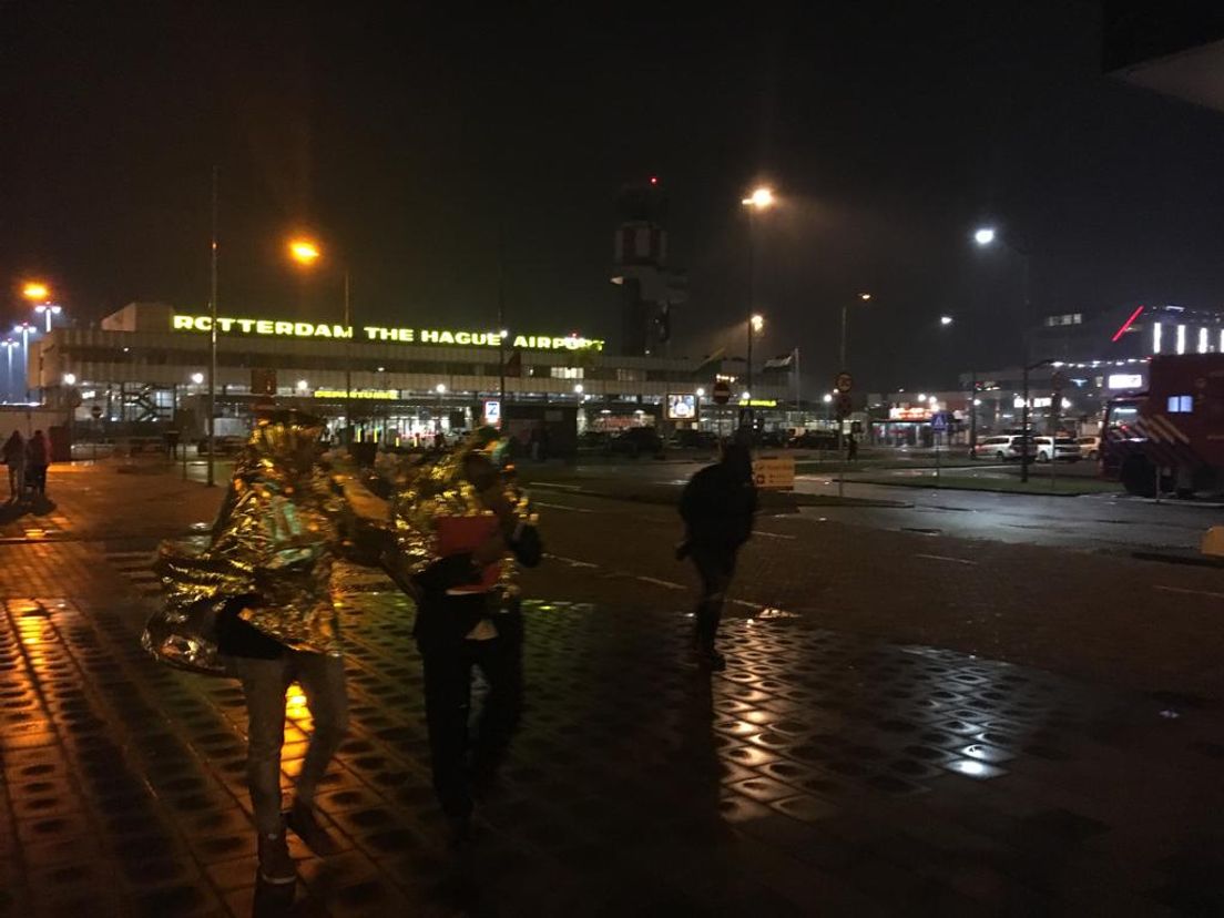 Mensen die naar buiten zijn gestuurd, krijgen een warmtedeken om.