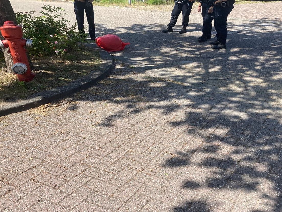 Agenten staan bij de buit, een rode tas met vermoedelijk papieren