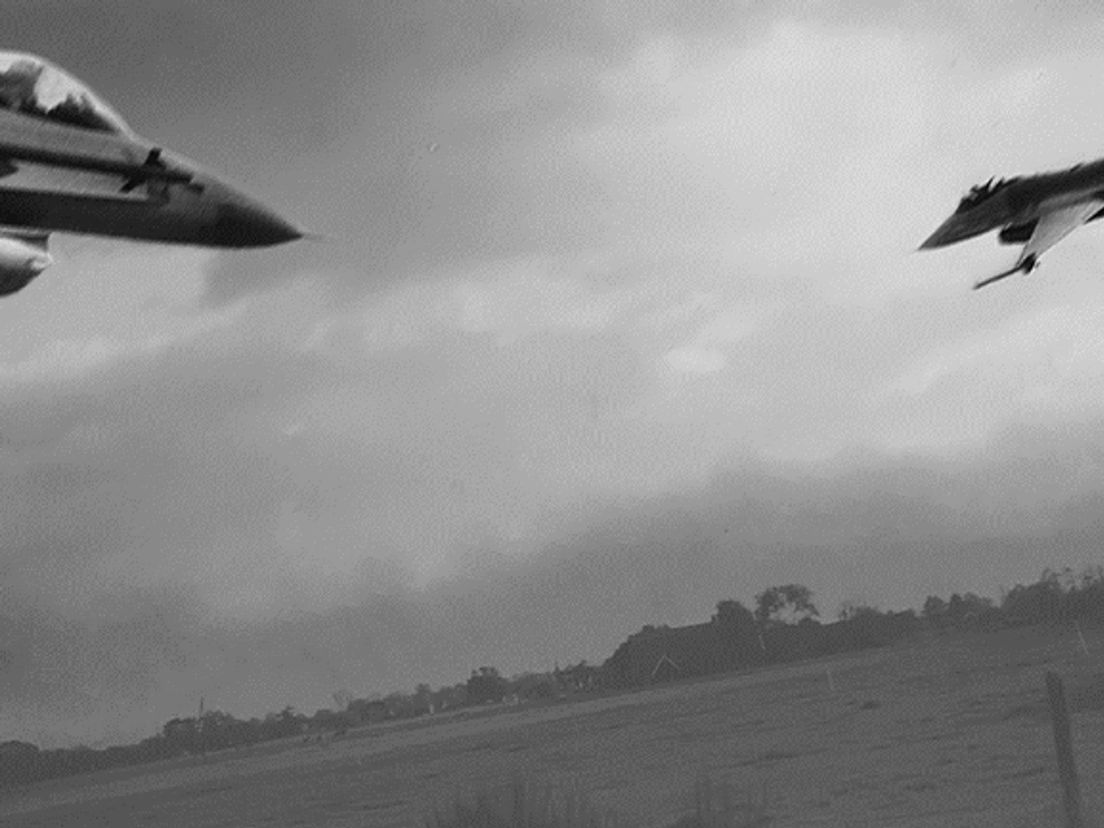 F-16's razen even later rakelings over de in de verte zichtbare hoogspanningsleidingen (Montage