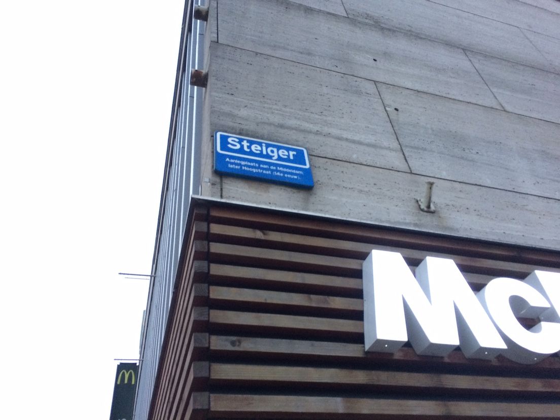Het naambordje, naast het deel van een logo van een niet nader te noemen restaurant met Amerikaanse keuken