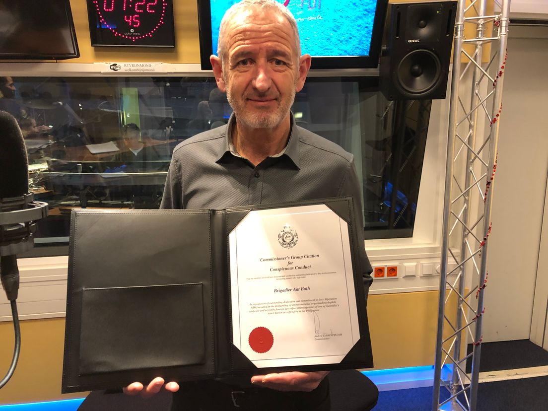Aat Both met zijn onderscheiding in de studio van Radio Rijnmond
