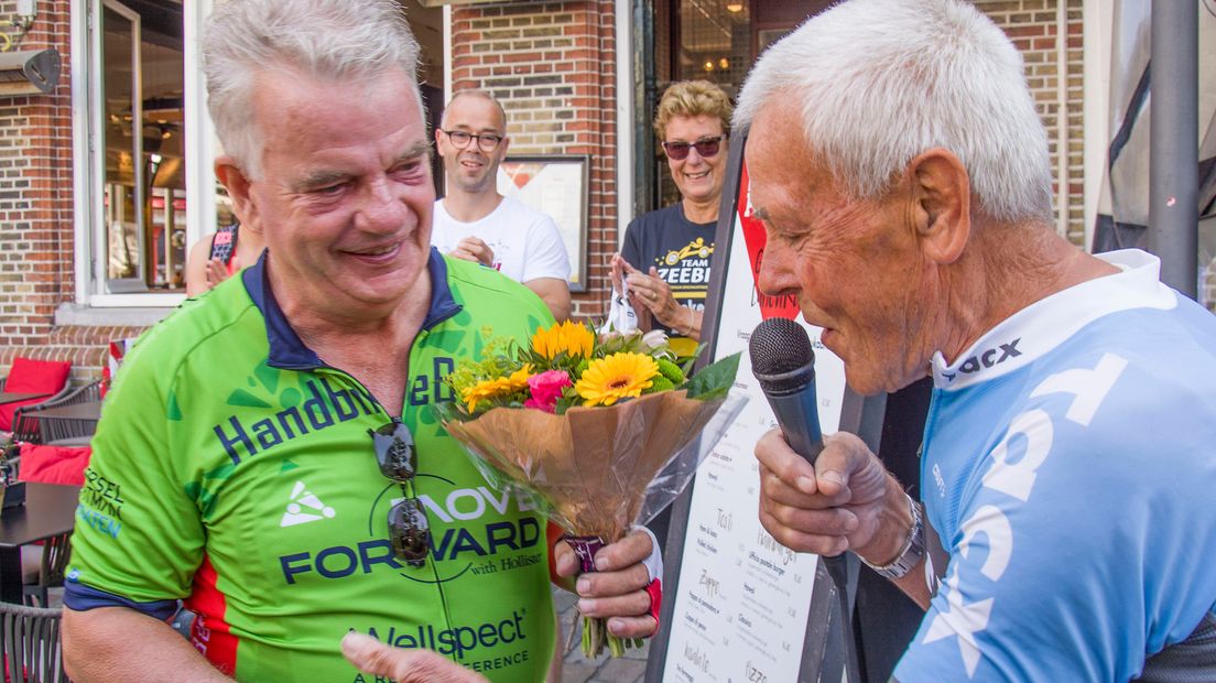 Jo de Roo (r) reikt een bloemetje uit aan handbiker Jan Simpelaar