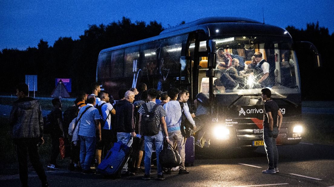 Asielzoekers stappen in een bus voor het aanmeldcentrum in Ter Apel