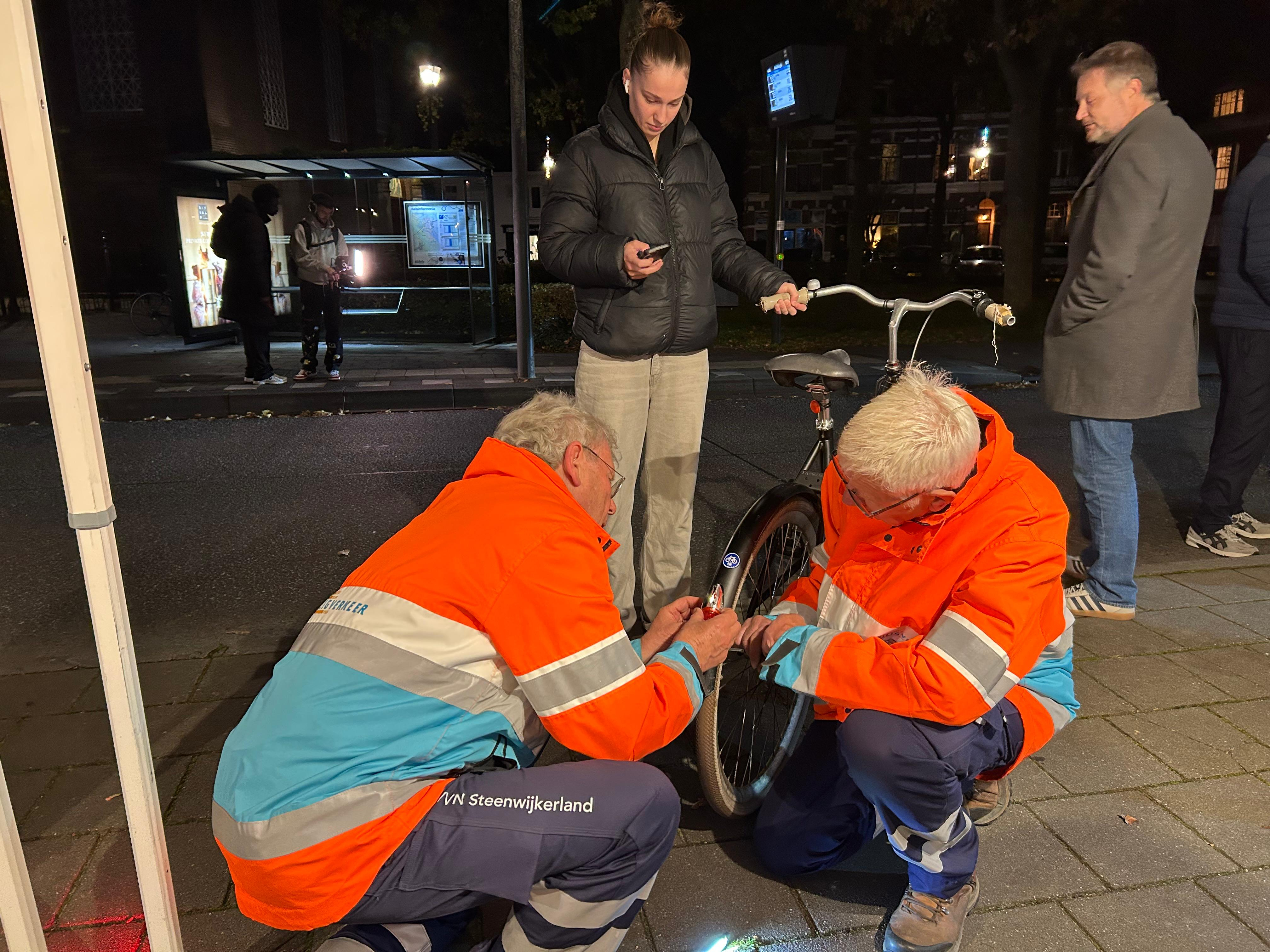 Vrijwilligers van Veilig Verkeer Nederland zetten een nieuwe lamp op de fiets.