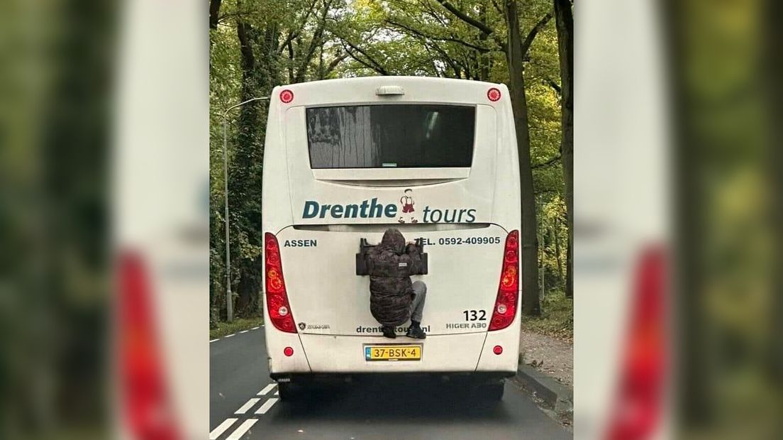 Man hangt aan bus Drenthe Tours in Emmen