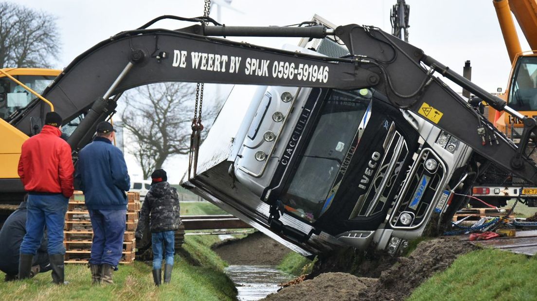 De vrachtwagen wordt met een kraan uit de sloot gehaald