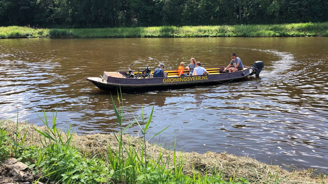 Wandelaars en fietsers maken gebruik van het eenmalige pontje over het Van Starkenborghkanaal