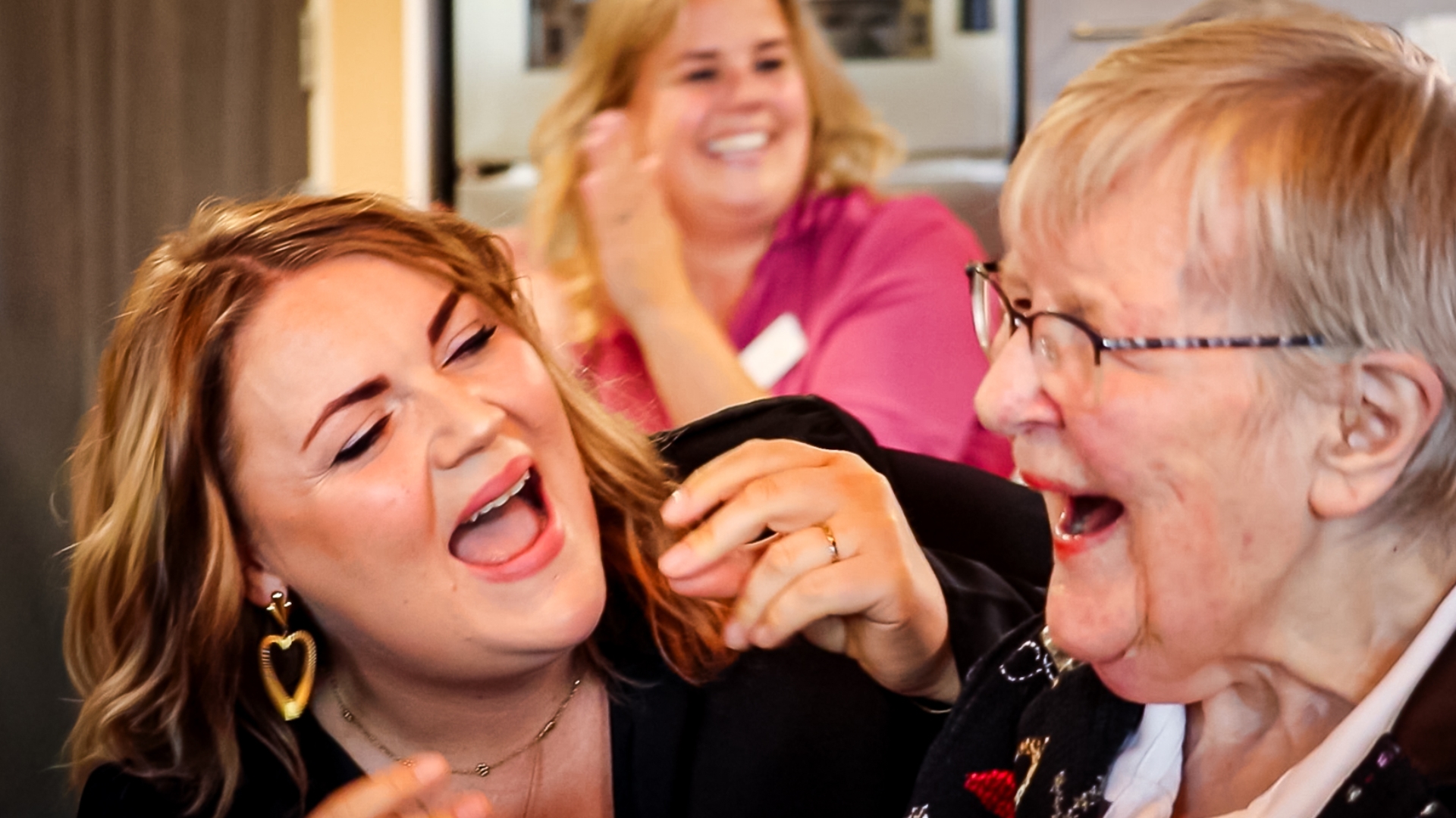 Bewoner en zorgmedewerker Lisanne Huizinga klappen en zingen mee met gezang Jeltsje Boschma