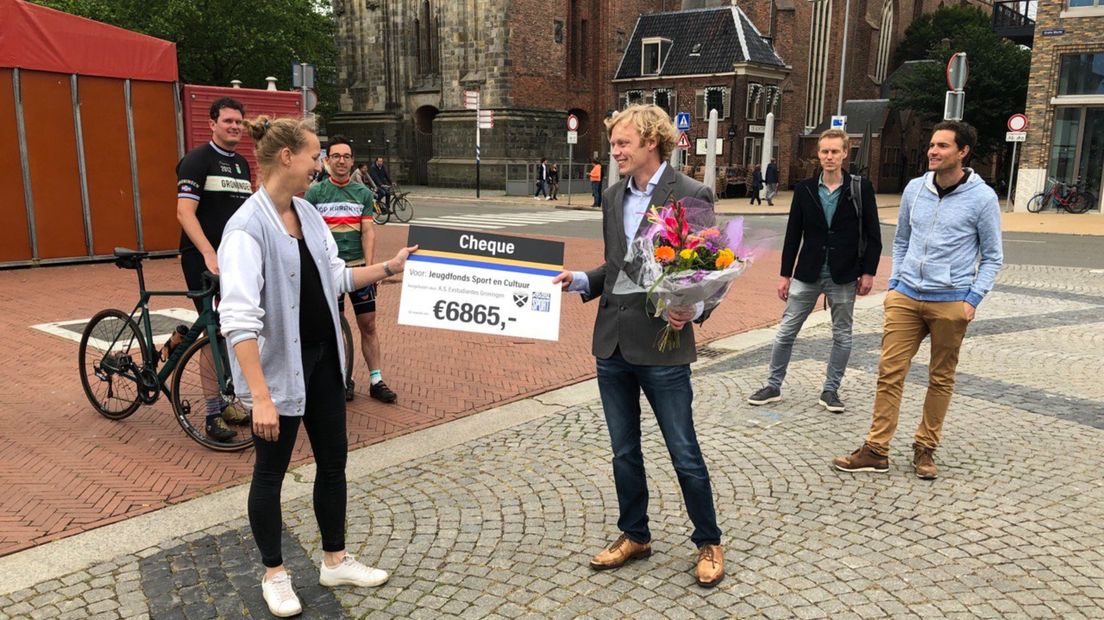 Een bestuurslid van Exstudiantes overhandigt de cheque aan Jeugdfonds Sport en Cultuur