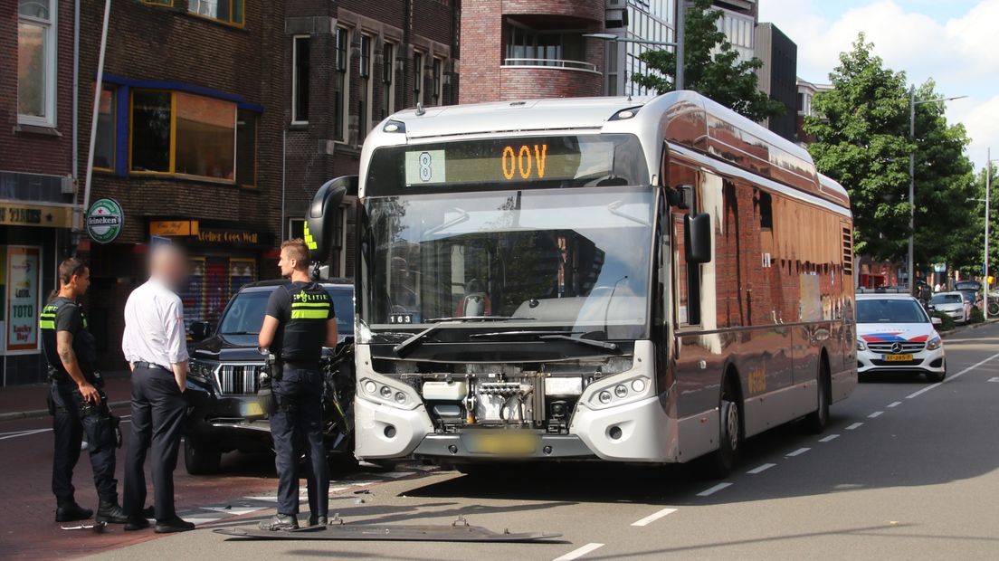 Politieagenten en de buschauffeur kijken toe nadat de botsing heeft plaatsgevonden