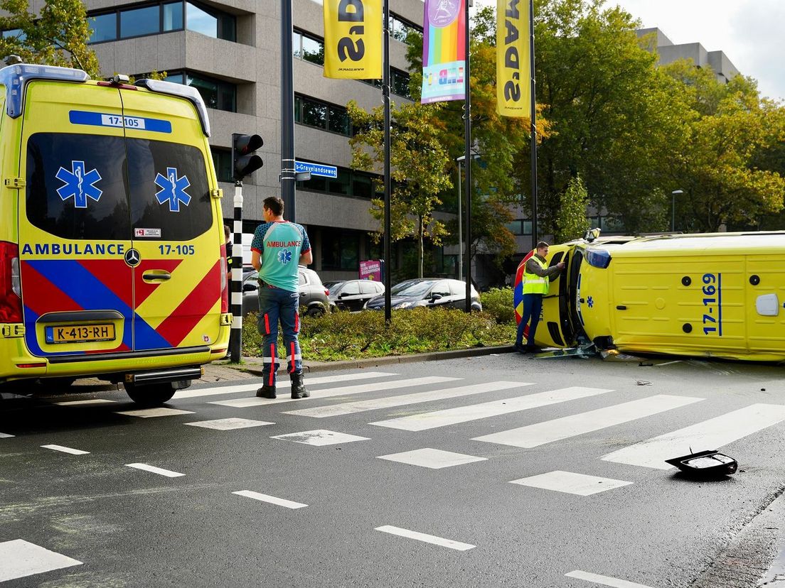 Een ambulance op weg naar een patiënt botste op een personenwagen en kantelde.