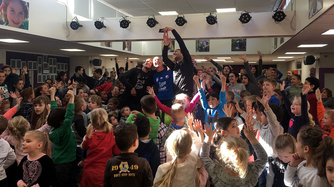 Ramon Leeuwin en Marcel Mul kijken hoe Willem Janssen een selfie maakt tussen de schoolkinderen in Houten.