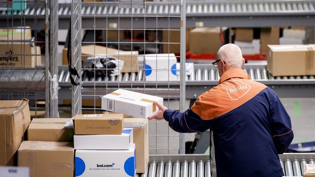 Een medewerker sorteert pakketten in een sorteer- en distributiecentrum van PostNL