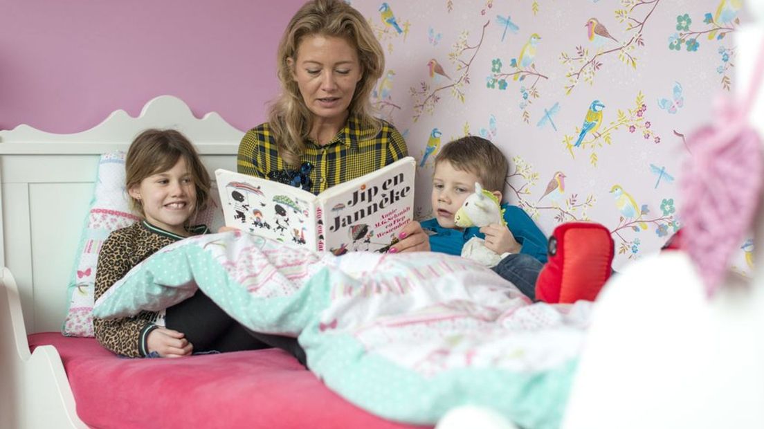 Een moeder leest haar kinderen voor uit Jip en Janneke.