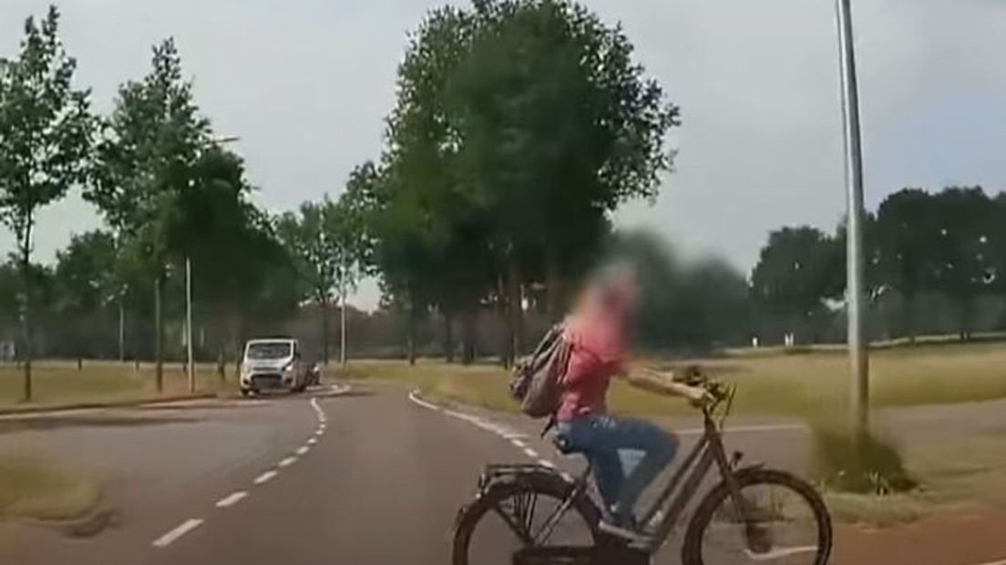Terwijl haar vriendinnen keurig wachten, rijdt deze fietsster tot tweemaal toe rakelings voor een auto langs.