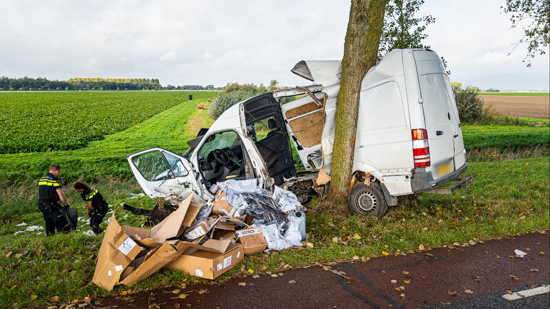 Op beelden is te zien dat de bestelbus bijna in twee stukken is geraakt door de boom en dat de weg ligt bezaaid met pakketjes.
