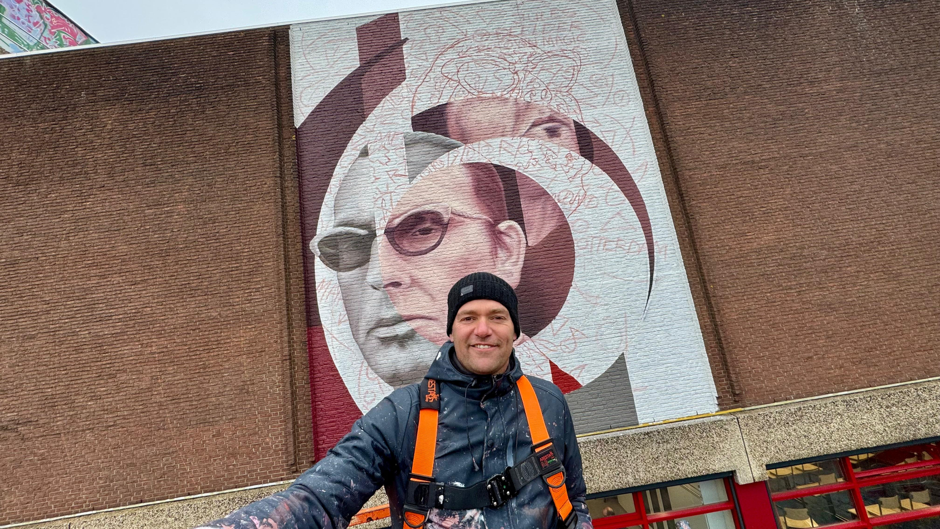 Kunstenaar Ricardo van Zwol bij zijn muurschildering van Jules Deelder